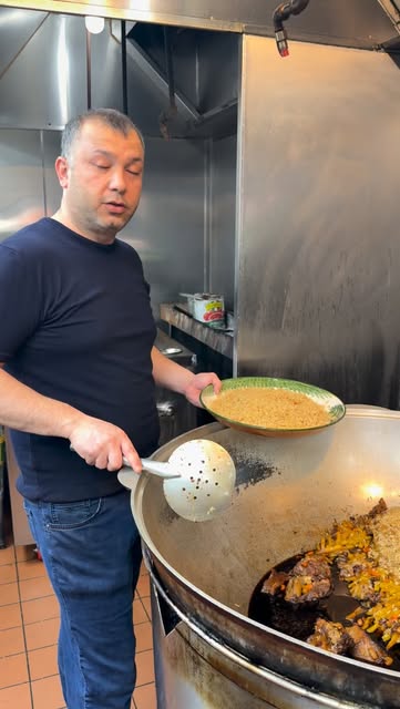 A cook lifting rice from the kazan with a long skimmer